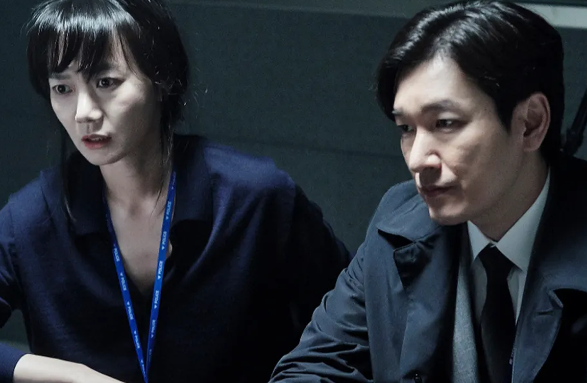 韓劇《秘密森林2》的劇照，呈現了兩名調查人員在案情討論中的場景，氣氛嚴肅且緊張。
