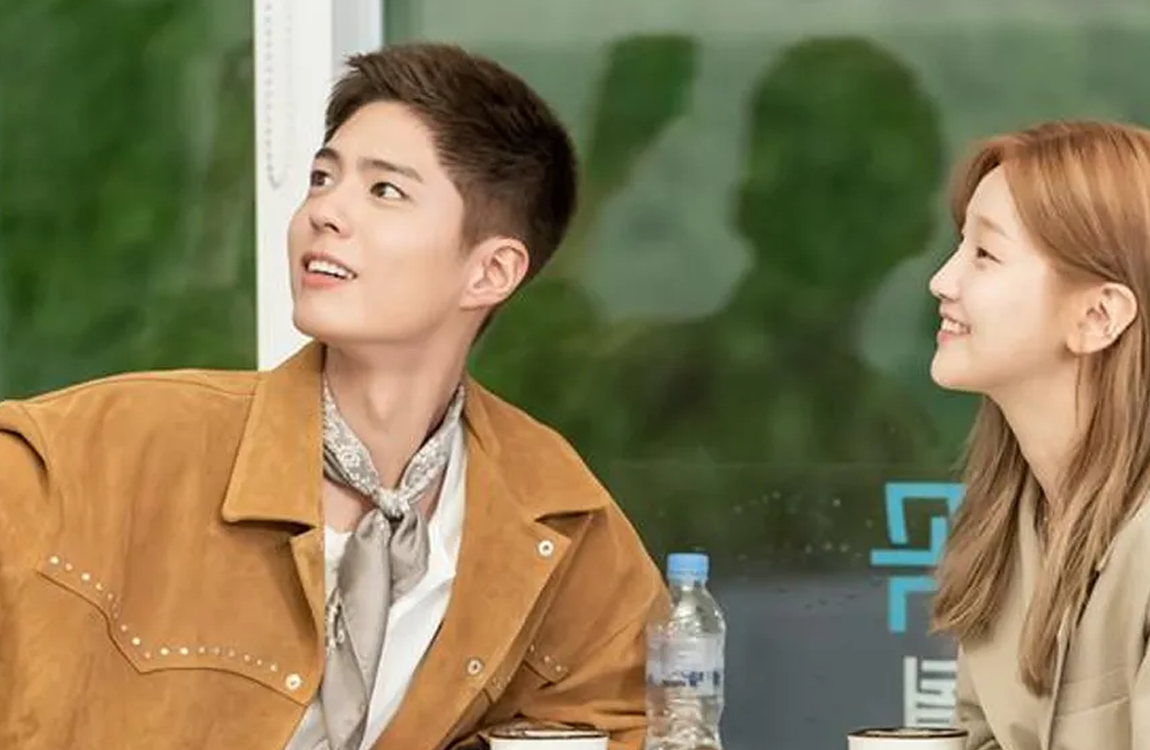 韓劇《青春紀錄》中，年輕人們正裝飾地並排坐著，背景為明亮的藍色天空和牆壁。