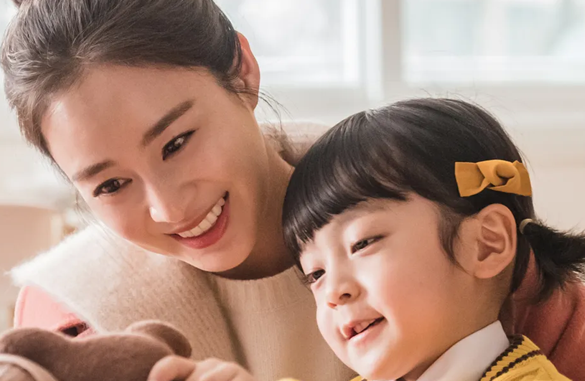 韓劇《再見媽媽又再見》中母親牽著孩子，兩人在家中温馨互動，流露出家庭的愛與親情。