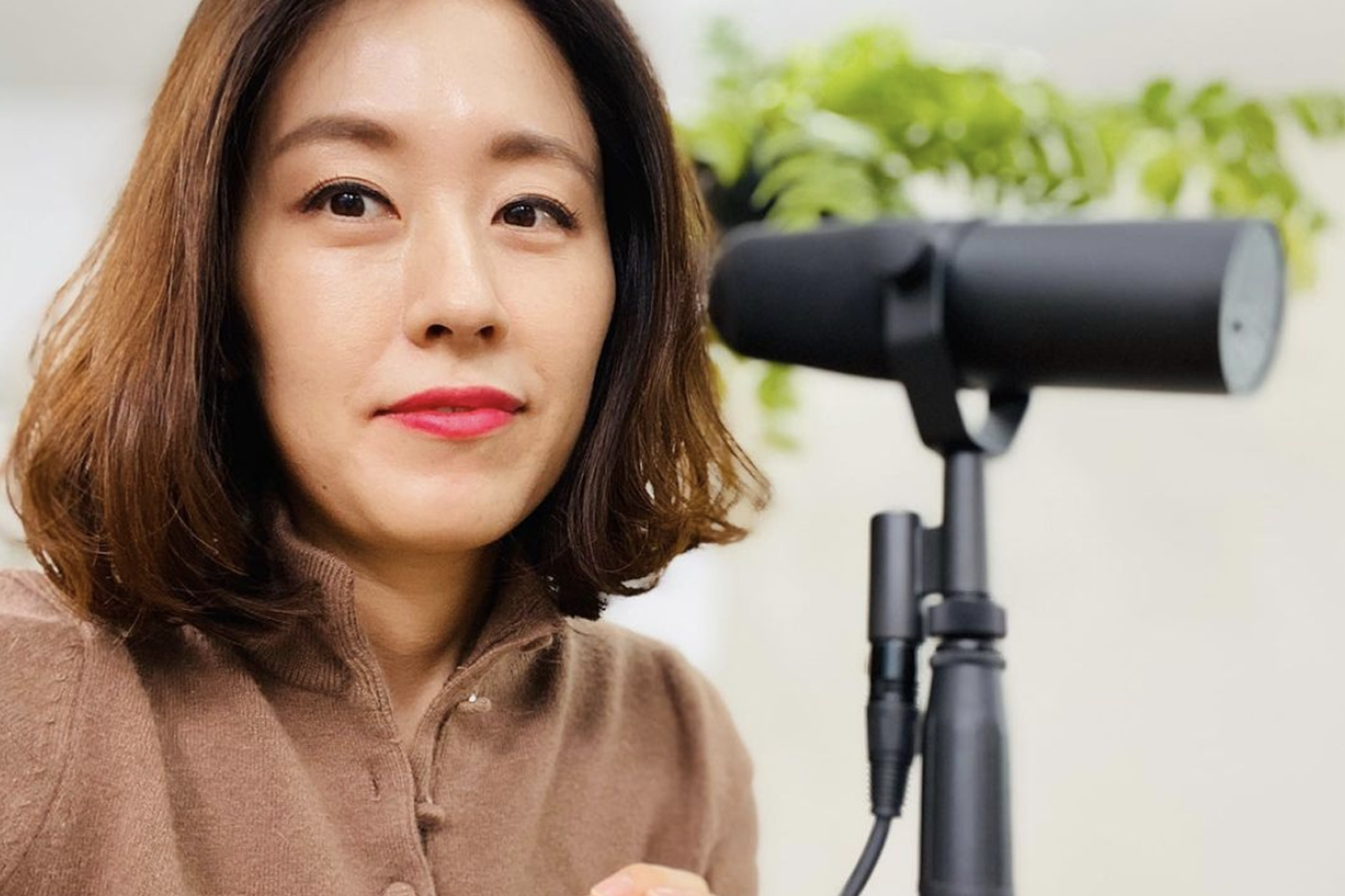 手持麥克風錄製韓語學習Podcast節目的情景，提供聽眾學習和提高韓語能力的工具。