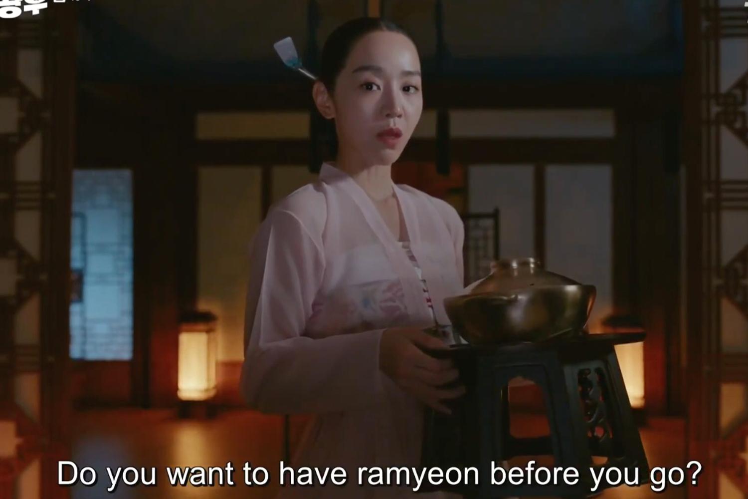 ฉากจากซีรีส์ที่หญิงสาวยืนถือหม้อรามยอน, คำบรรยายภาษาอังกฤษว่า 'Do you want to have ramyeon before you go?' ขณะอยู่ในห้องสไตล์เกาหลีดั้งเดิม