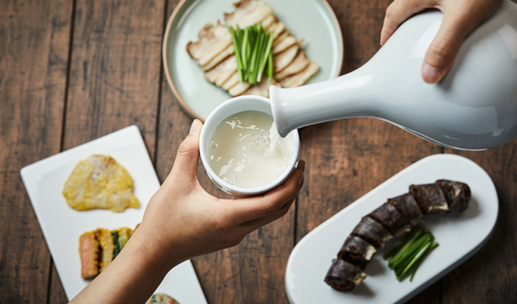 醇厚濃鬱的韓國傳統米酒正在倒入杯中，搭配各種美味韓國小菜，展現正宗的飲食文化。提供豐富營養與飲用樂趣的韓國酒 (Makgeolli)，中文盒子的概念是一直陪伴在你左右。