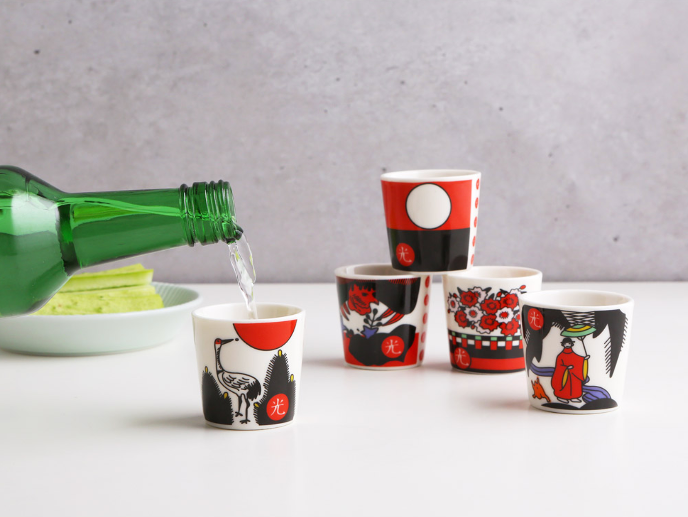 香港中環日本花牌燒酒杯展示圖,展示具有傳統圖案的燒酒杯,背景為白色,並有青瓜的一部分可見。