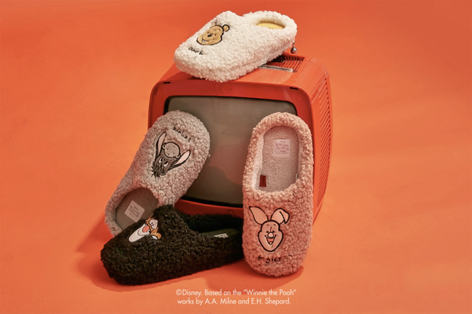 香港中環Disney小熊維尼聯名室內拖鞋展示圖,有灰色、白色及粉紅色的款式,背景為橙色。
