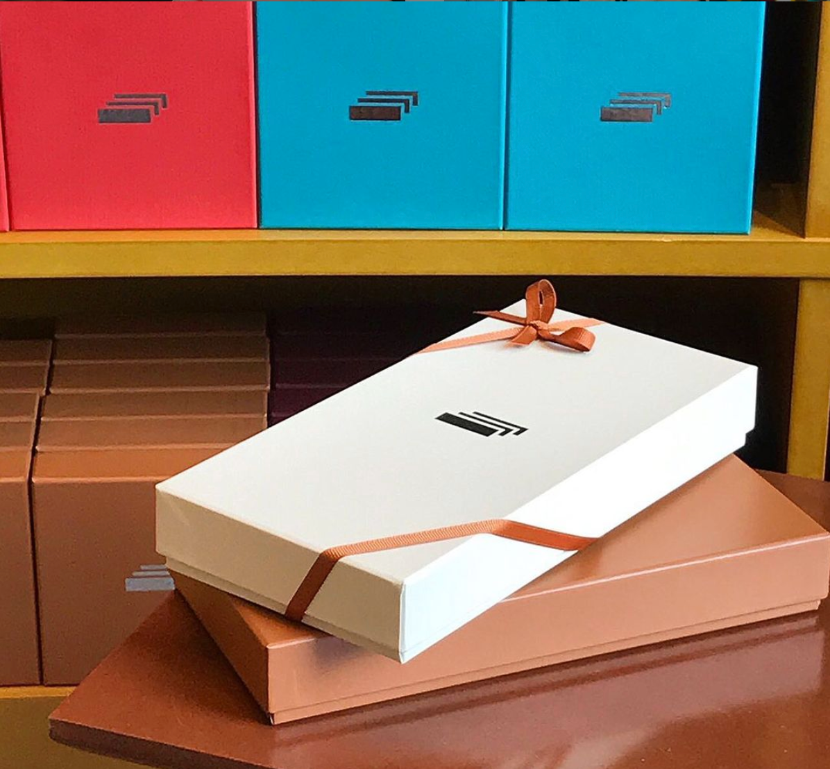 香港中環Index Caramel牛奶糖禮盒展示,伴隨著一個高雅的白色及銅色禮盒包裝,背景為多彩排列的禮盒。