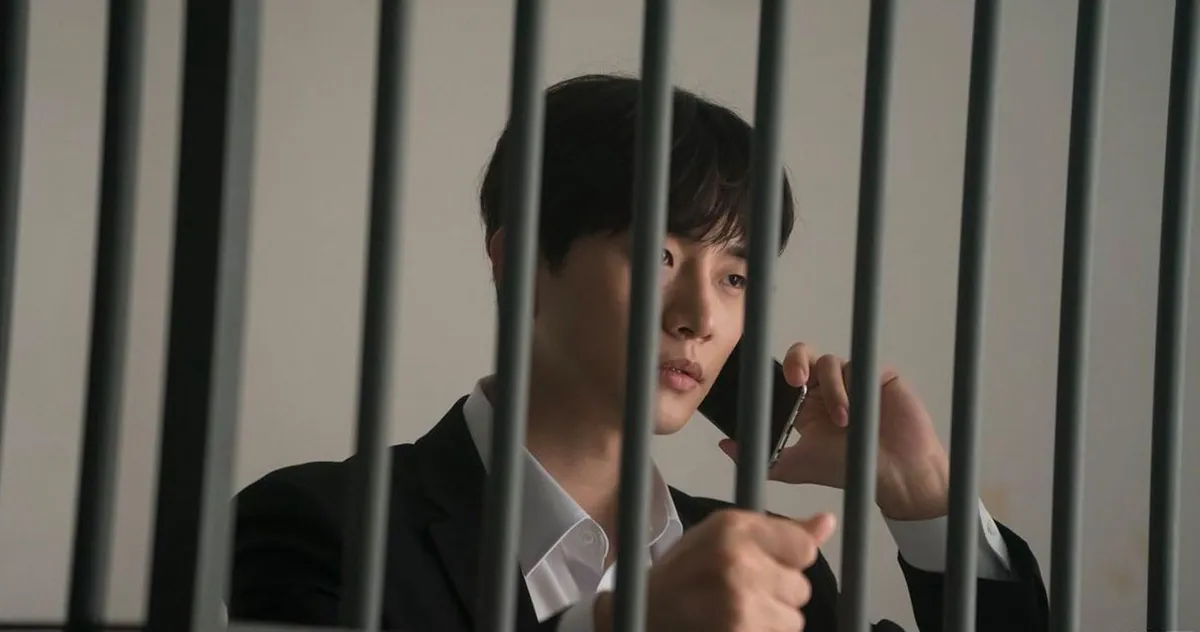 一名穿西裝的男子在監獄的鐵柵欄後面通話，象徵因酒駕被捕的人。