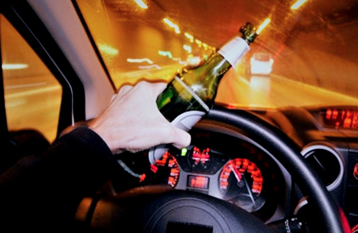 在駕駛中手持啤酒瓶，反映酒駕行為的危險性。