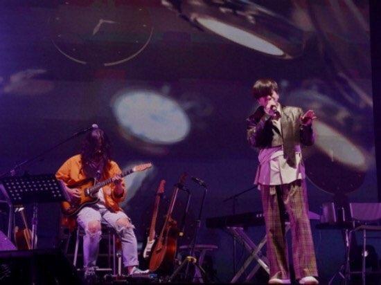 尹度玹演唱會上表演場景，背景屏幕上有樂器圖案投影