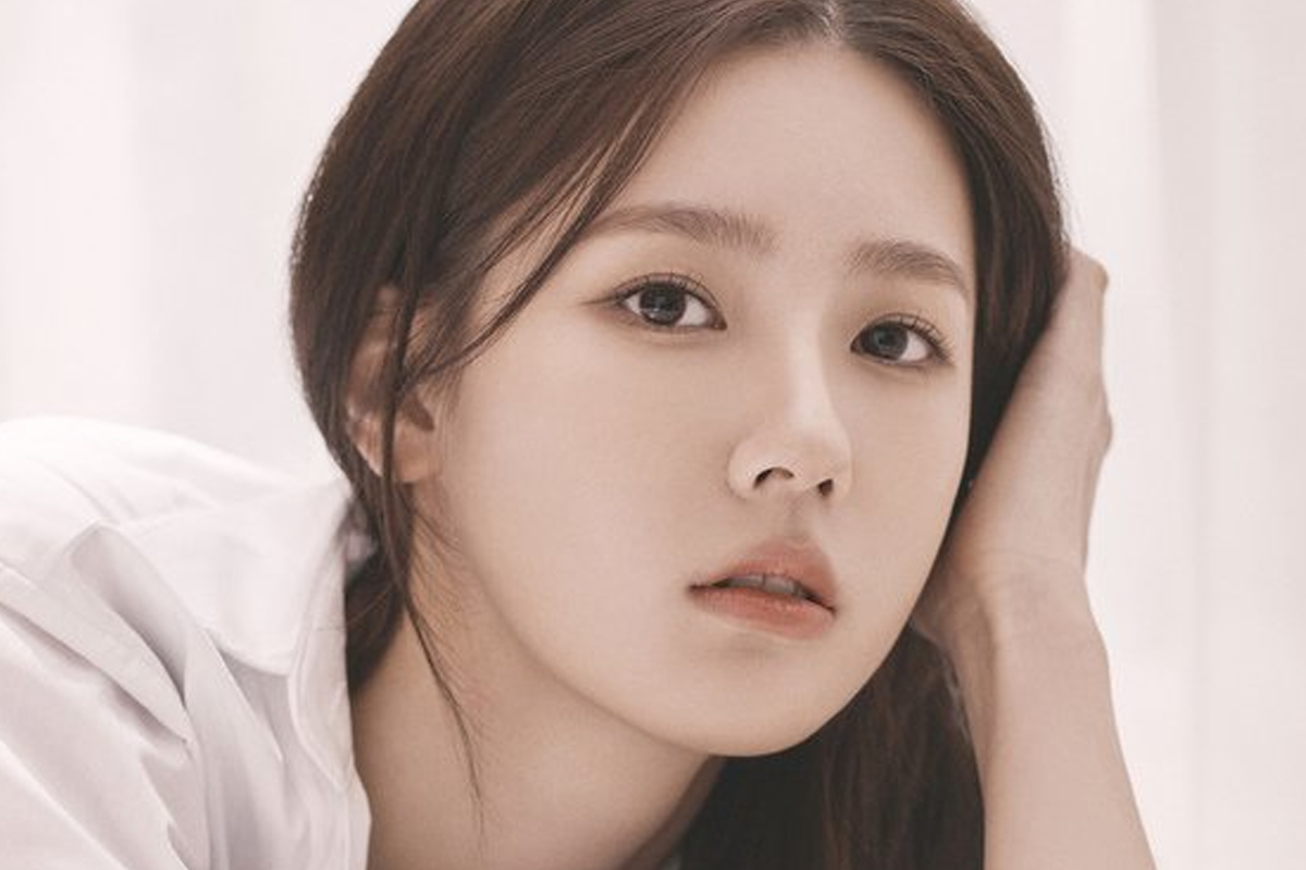 (G)I-DLE成員薇娟身穿駝色毛茸外套,站在森林裡,手中把玩著樹葉,營造出秋天的自然氛圍。