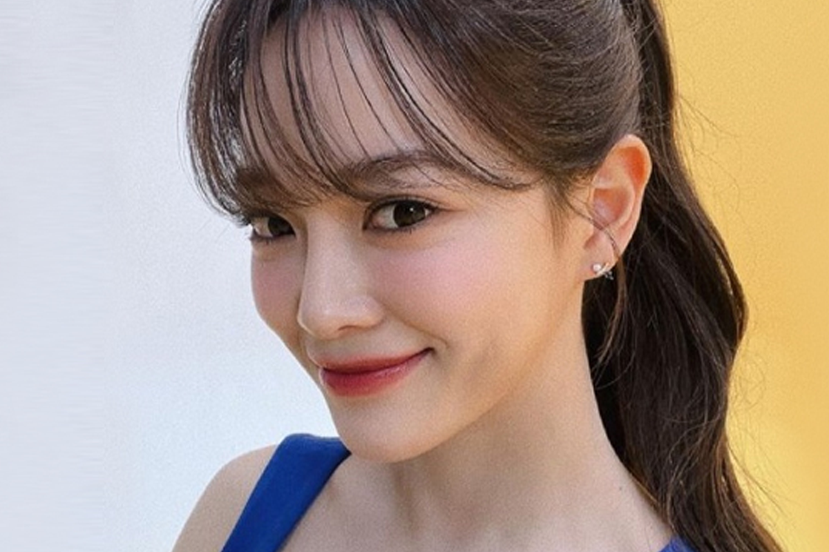 韓國女歌手世正身穿藍色背心裙,耳戴小巧耳飾,背景為黃色,給人明亮而清新的感覺。