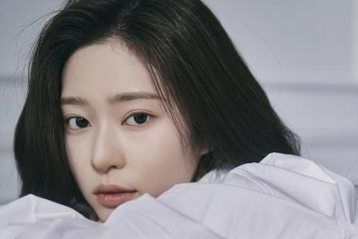 韓國女明星穿著白襯衫在桌面上,背景為室內環境,眼神流露出深邃和專注,顯得典雅且舒適。