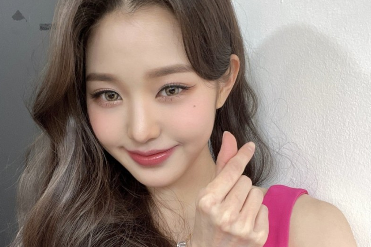 韓國女明星配戴皇冠,身著白色禮服,背景為橙色窗簾,展現高貴典雅的氣質。