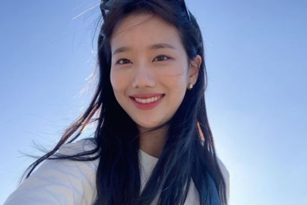 韓國女明星穿著暖色毛衣,擺出自然的微笑,背景為明亮的藍天,展現青春洋溢的魅力。