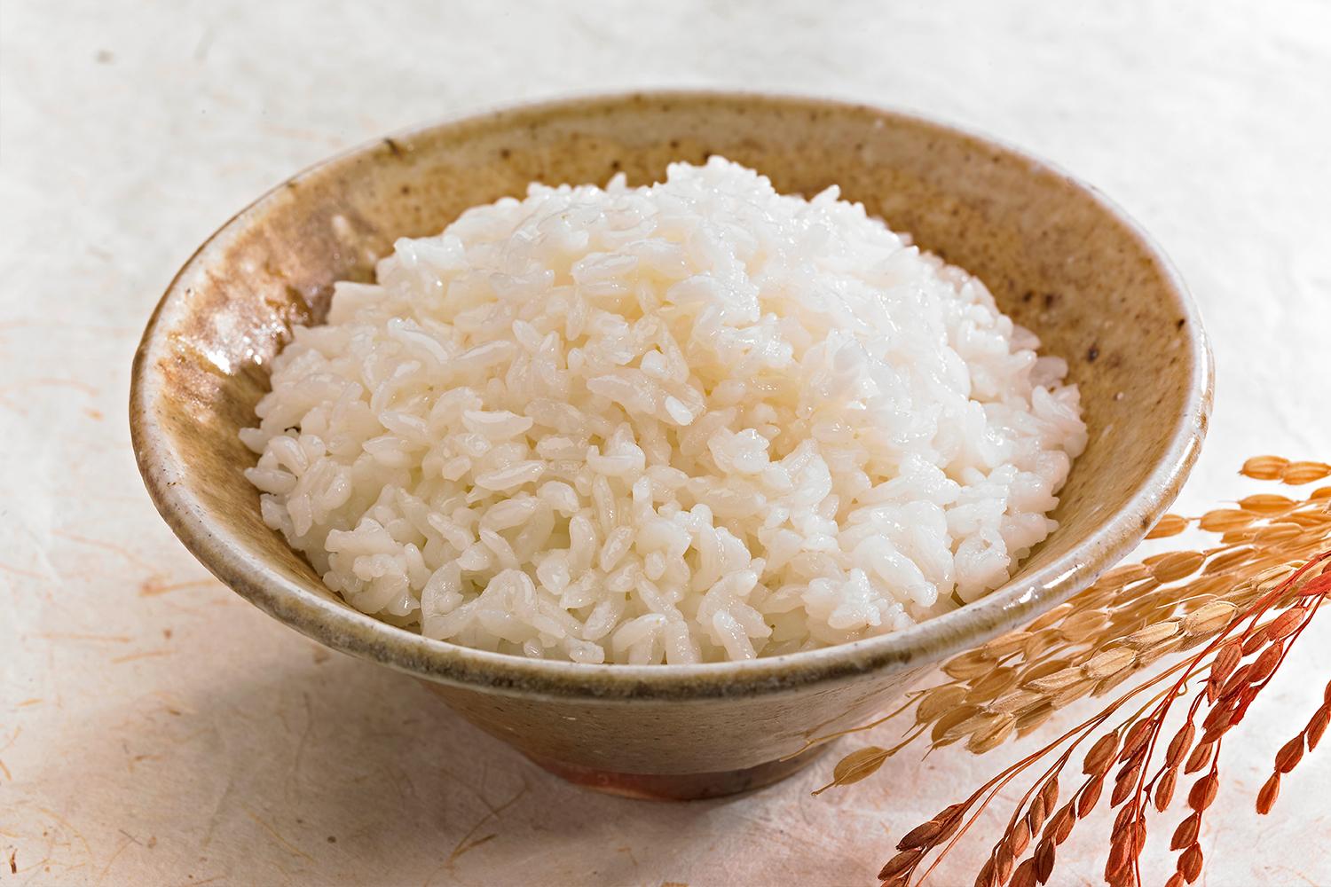 ข้าวสวยนุ่มในชามเซรามิกพร้อมด้วยข้าวต้นข้าวที่ตกแต่งด้านข้าง สะท้อนถึงประเพณีการกินของชาวเกาหลีที่ใช้ข้าวเพื่อช่วยเหลือในการกลืนก้างปลา