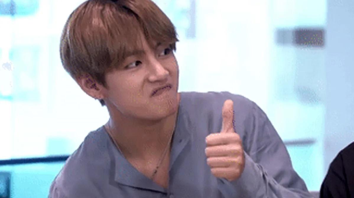 ชายชูนิ้วโป้งเสื้อเชิ้ตสีเทาในบรรยากาศออฟฟิศ