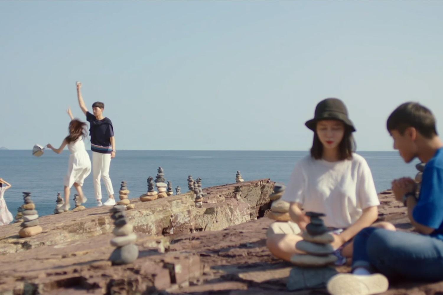 เด็กกลุ่มหนึ่งนั่งเล่นอยู่ริมทะเลพร้อมกองหิน, การท่องเที่ยวและกิจกรรมกลางแจ้งในบรรยากาศธรรมชาติ, วิถีชีวิตสบาย ๆ ของเด็กเกาหลี