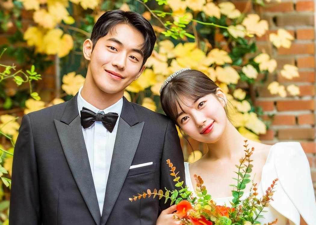 新婚中的一對新人，身穿正式的禮服和婚紗，站在布滿秋天葉子的背景下。