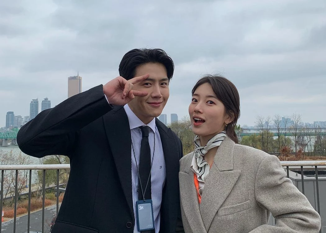 兩位角色站在戶外，背景是城市天際線，角色穿著正式的商務裝。