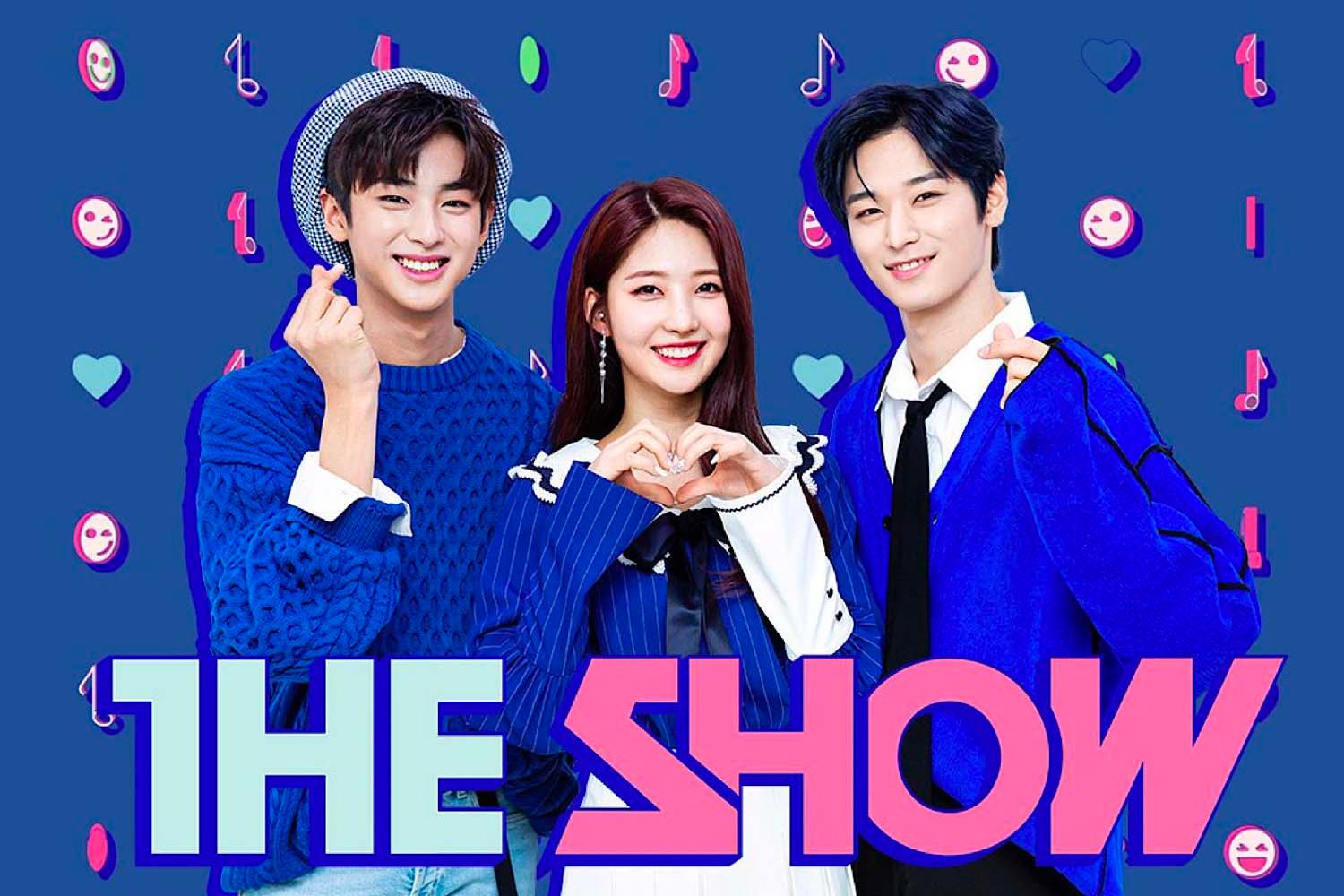 ทีมผู้ประกาศข่าวของรายการ THE SHOW ในชุดเสื้อสีฟ้าทำท่าทางสัญลักษณ์มือรูปหัวใจ
