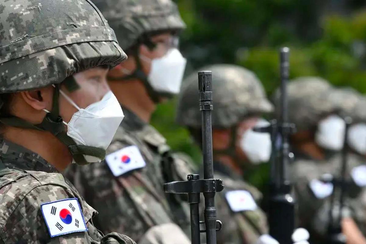 韓國軍人在儀式上戴著面罩整齊列隊的照片，背景是綠色植被。