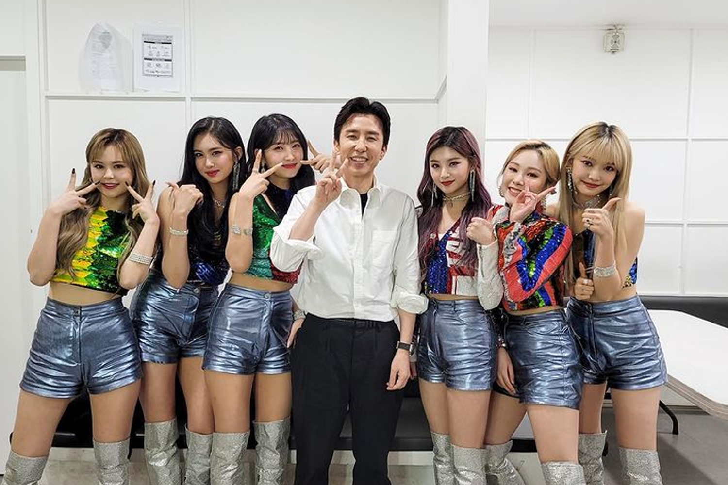 韓國偶像組合Everlow的成員身著紅色表演服站在一起，背景有韓文字樣的招牌。