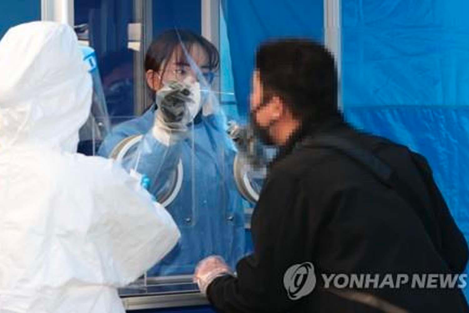 สถานที่ทดสอบ COVID-19 ในเกาหลีใต้ เจ้าหน้าที่สวมชุดป้องกันเต็มรูปแบบทำการตรวจสอบ