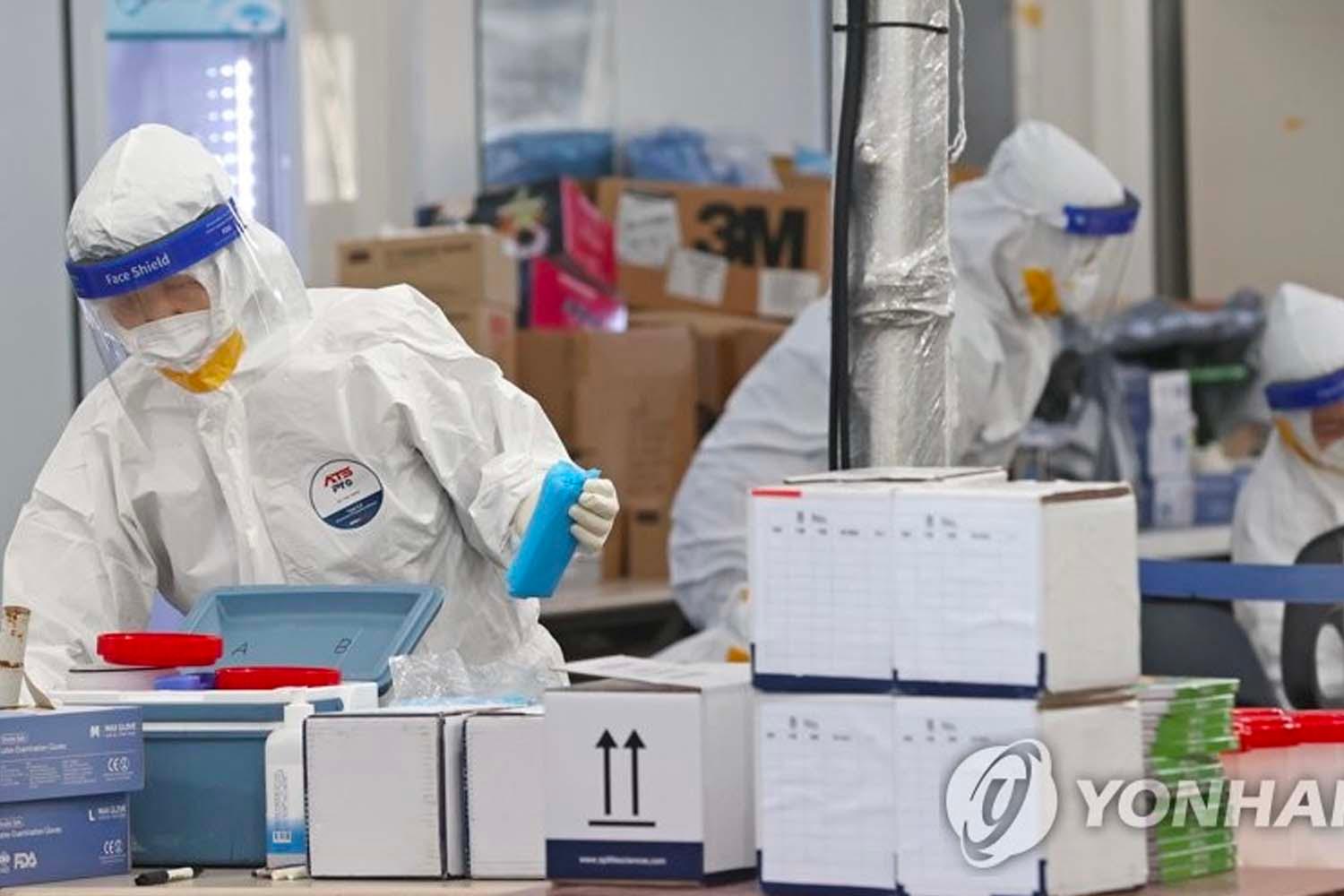 เจ้าหน้าที่เกาหลีใต้ในชุดป้องกันทำงานในศูนย์ทดสอบ COVID-19 ภาวะการแพร่ระบาดในประเทศ