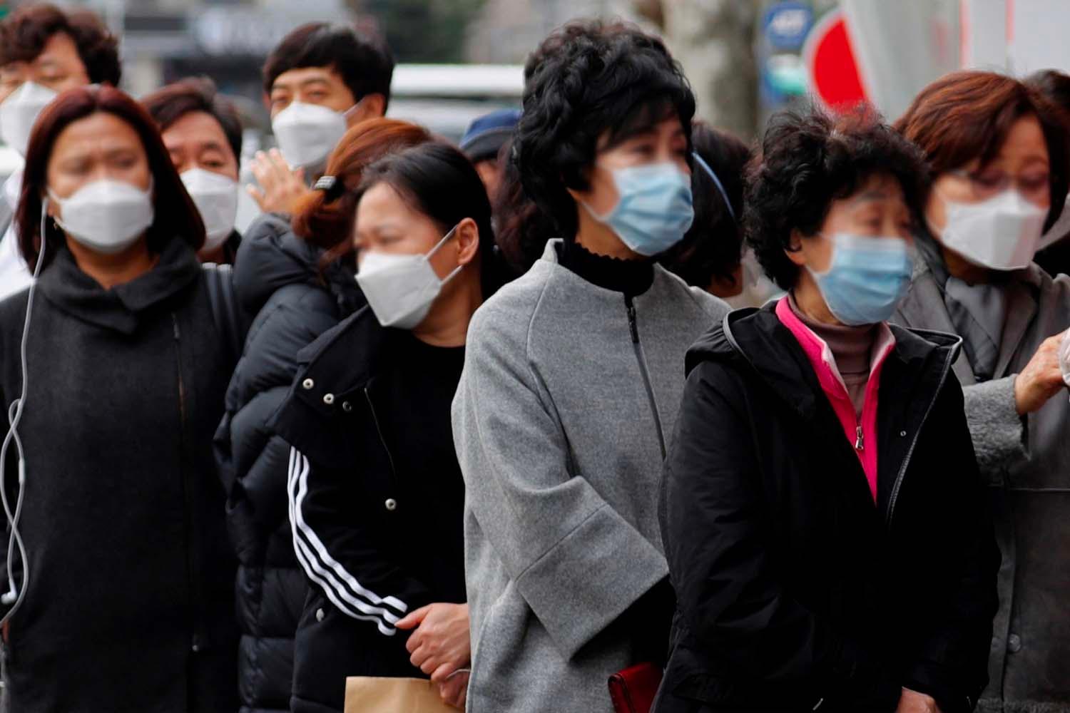 ผู้คนครอบครัวสวมหน้ากากยืนรอบริการตรวจ COVID-19 อยู่ในแถวประเทศเกาหลีใต้