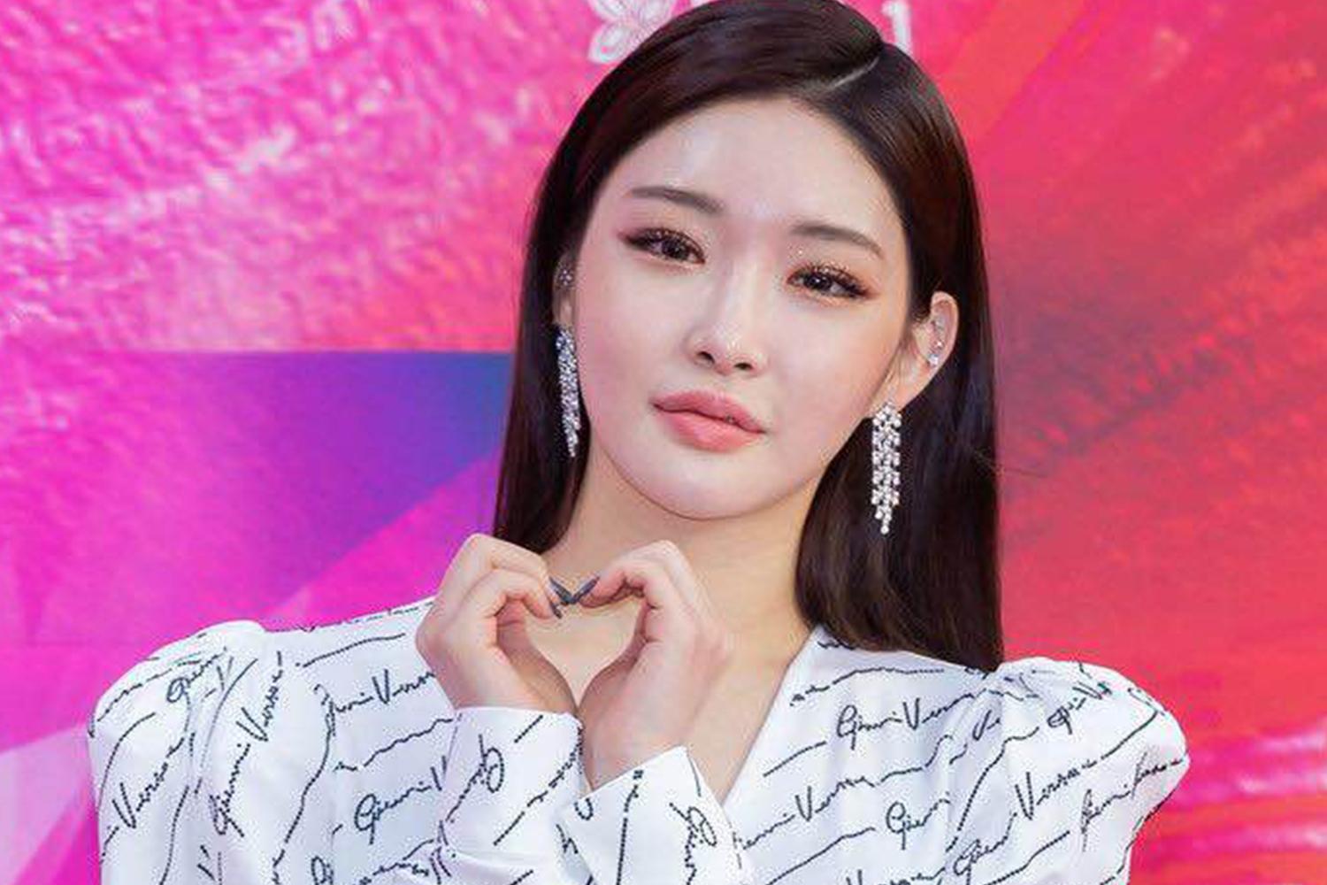 韓國女歌手手勢比心穿著白色字母印花服飾背景色彩繽紛