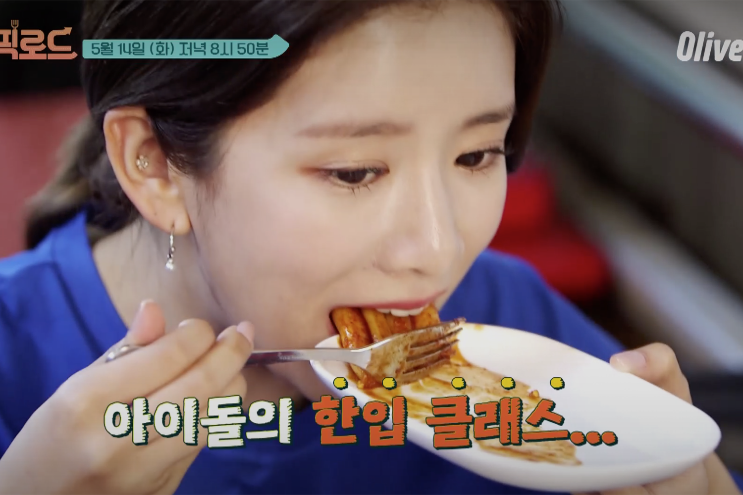 韓國女藝人EXY用筷子夾起辣炒年糕，背景是餐廳內部場景