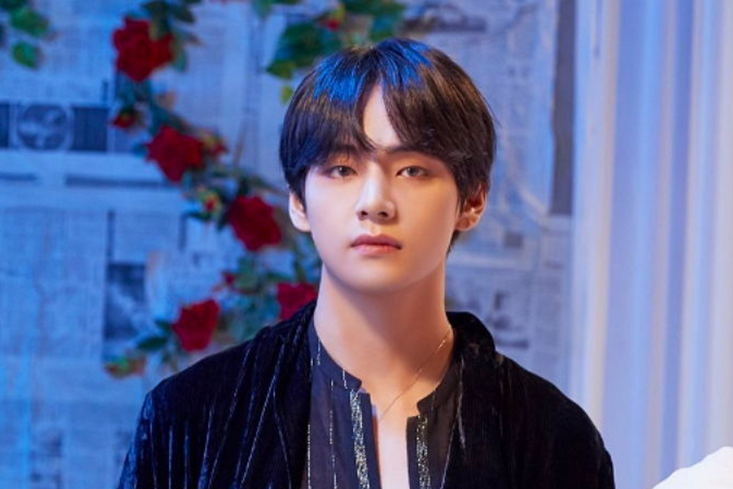 BTS的V身穿黑色絨面外套，背景擺設有紅色花朵裝飾，營造出華麗氛圍。這位全球知名的韓國男歌手在投票結果中排名第1位。