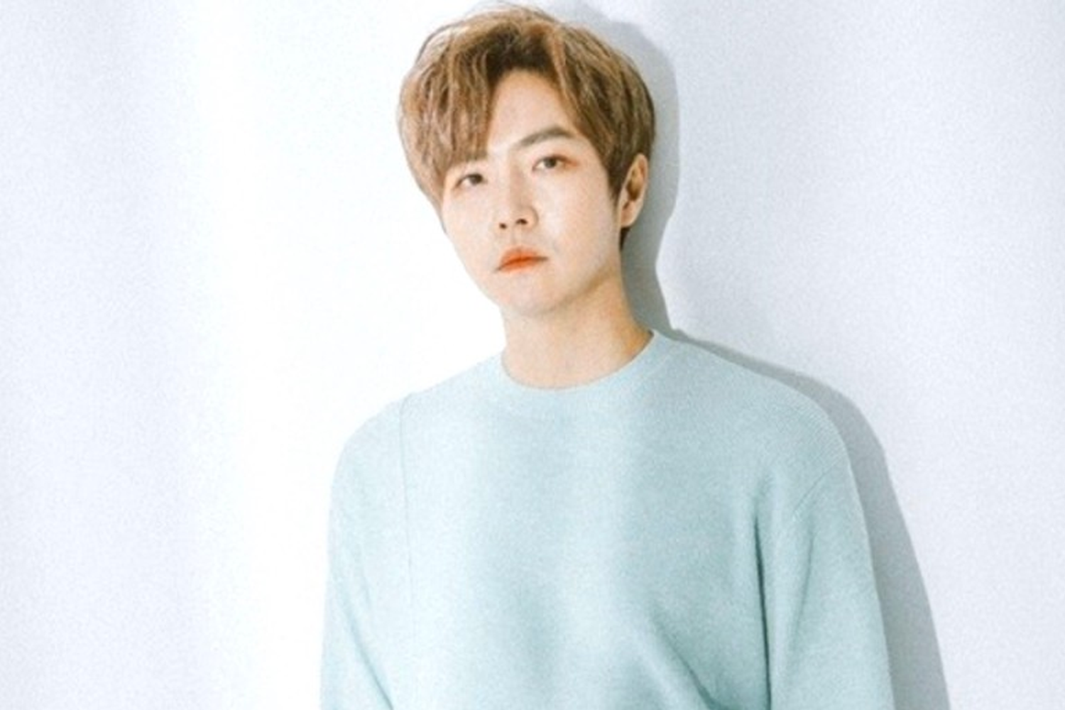 鄭東河穿著淡藍色毛衣，站在白牆旁邊，顯得温柔淡雅。這位韓國男歌手在投票結果中排名第10位。