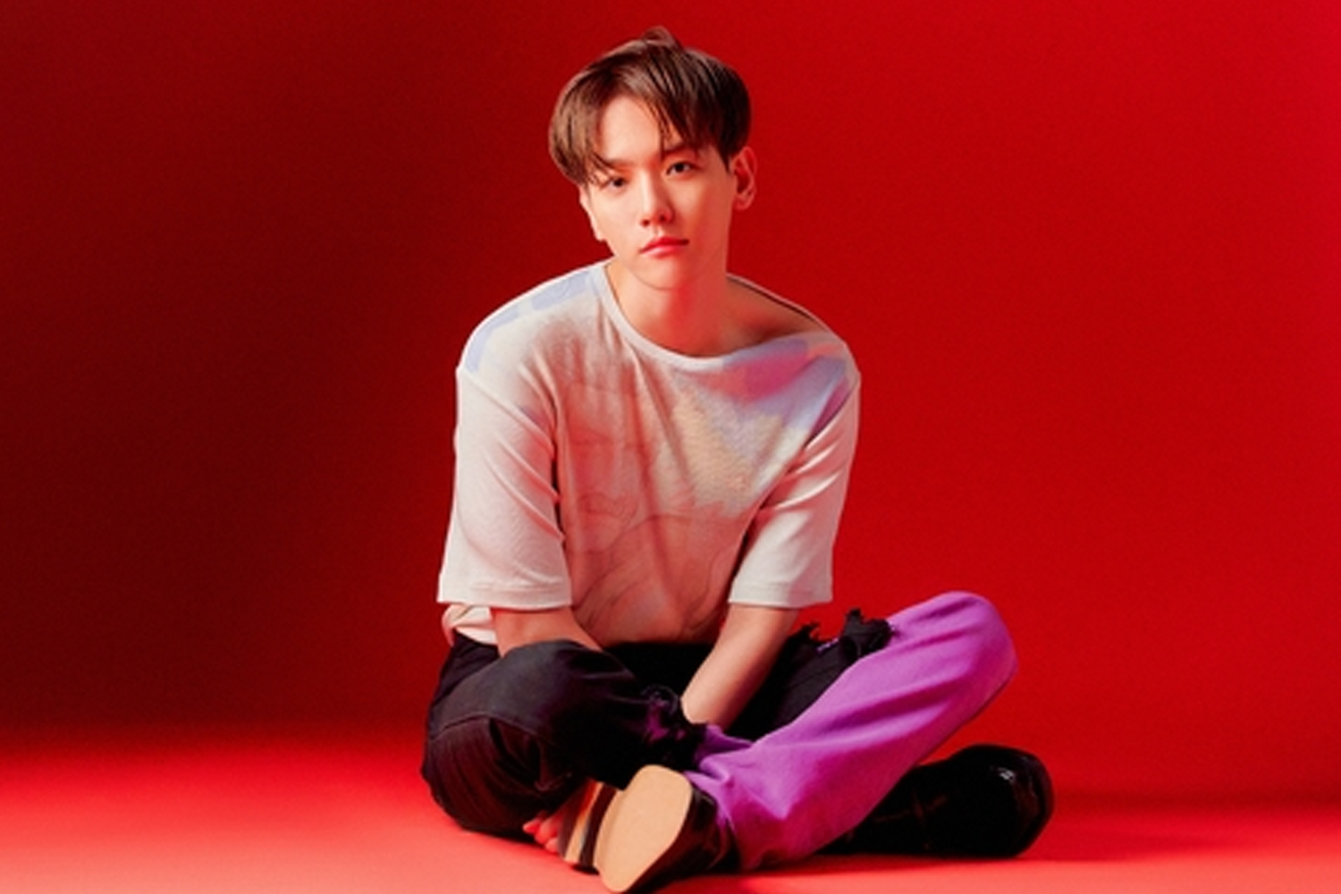 EXO的伯賢坐在紅色背景下，穿著白色上衣和紫色褲子，展現出色的舞台姿態。這位韓國男歌手在投票結果中排名第13位。