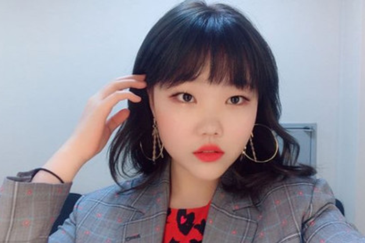 AKMU的秀賢穿著格子西裝外套，手放在頭髮上，展現清新風格。這位韓國女歌手在投票結果中排名第14位。