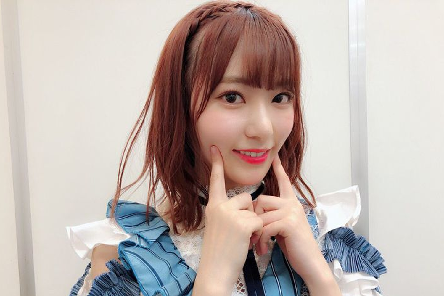 IZ*ONE的宮脇咲良身穿藍色花邊衣服，雙手放於下巴旁，顯得可愛俏皮。這位日本女歌手在投票結果中排名第15位。