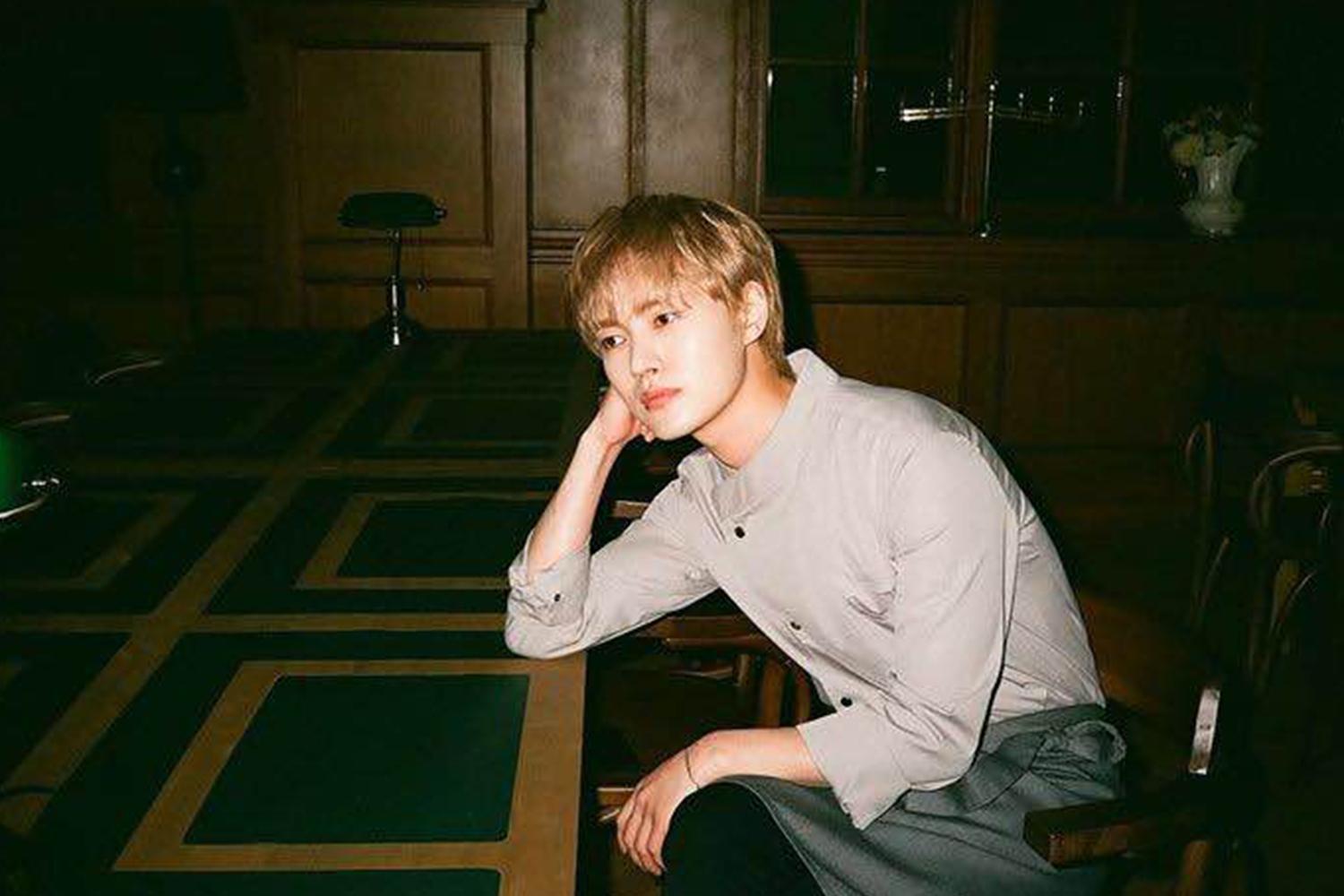 李泰利穿著淺色襯衫坐在房間內