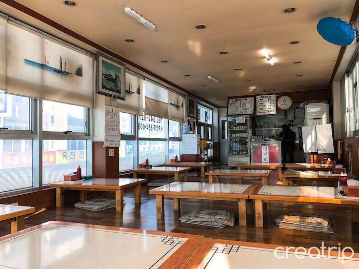 Interior view of Tongyeong's Central Raw Fish Restaurant with traditional seating arrangements.
