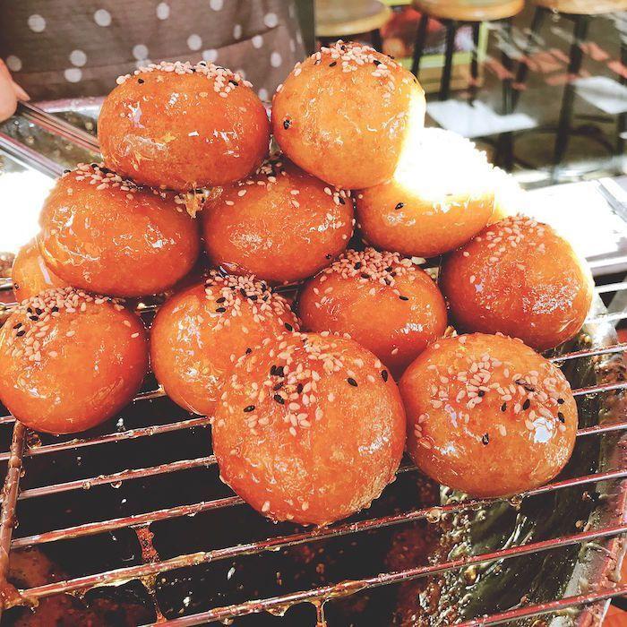 Freshly baked honey buns covered in glaze and sesame seeds for sale.