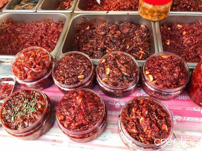 Assorted Korean spicy sauces and fermented seafood products in jars.