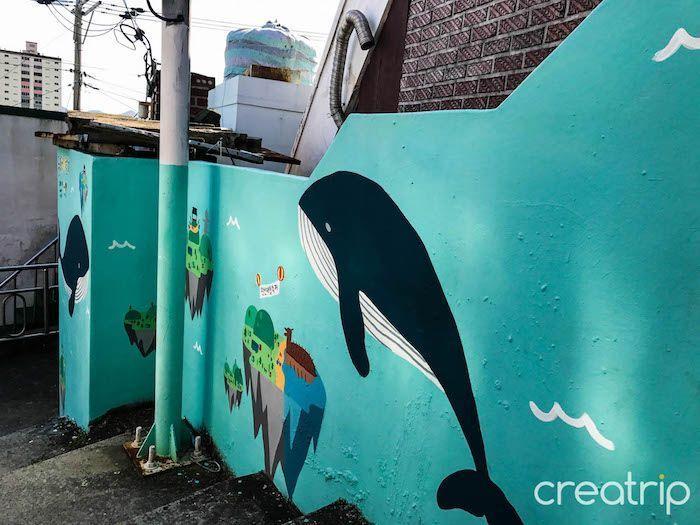 Brightly painted mural of a cartoon whale and colorful designs on a wall in Dongpirang Mural Village, Tongyeong.