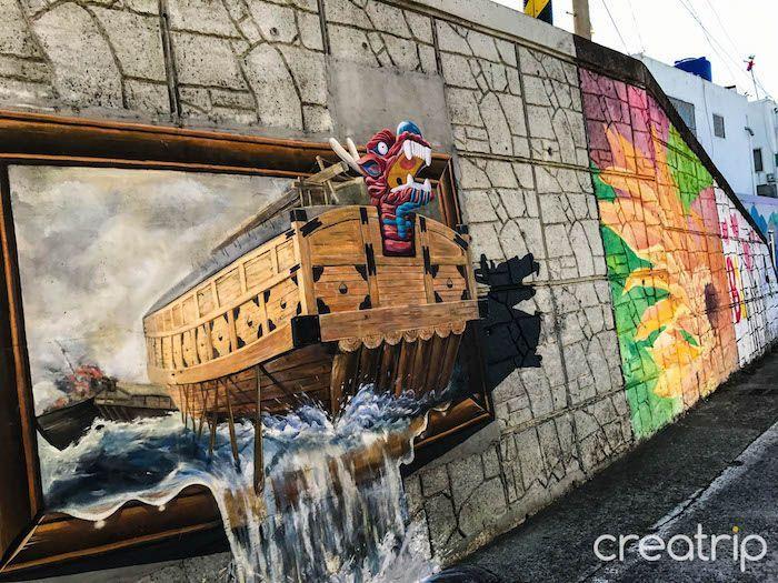 Vivid mural artwork depicting historical naval battles and creatures in Dongpirang Mural Village, Tongyeong.