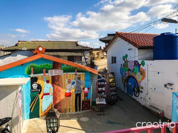 Open area in Dongpirang Mural Village with various murals painted on building walls and welcoming atmosphere.