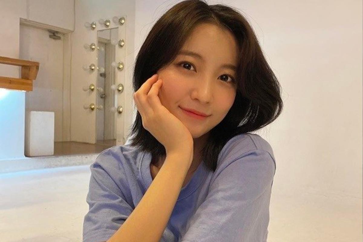 穿著淺藍色T恤的女孩，短髮造型時尚，背景為室內裝飾明亮。