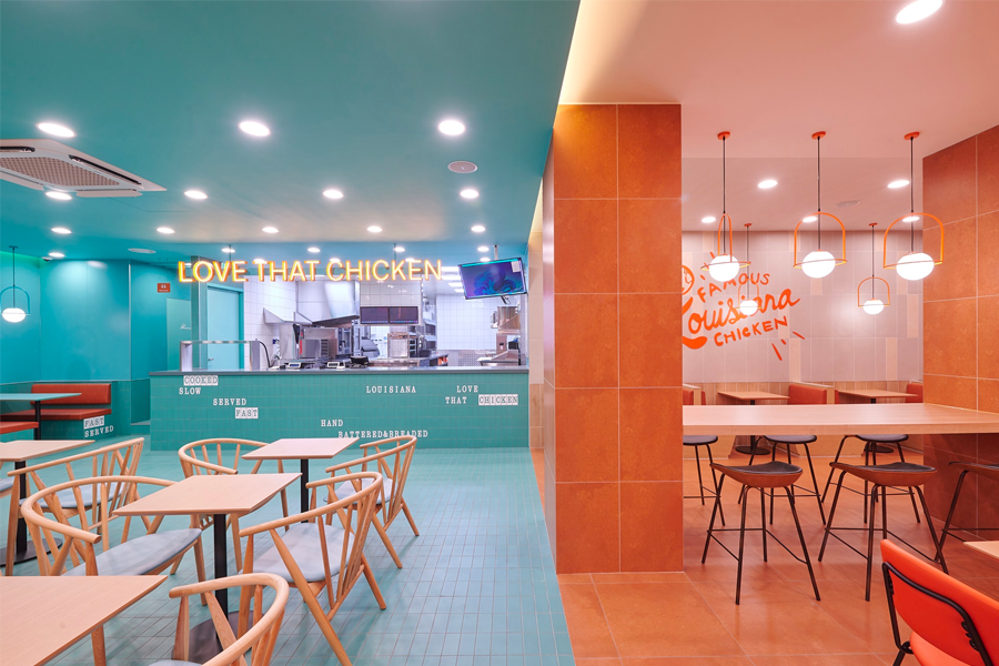 Popeyes韓國江南站店的內部設計，帶有霓虹燈字體'LOVE THAT CHICKEN'的座位區，展示休閒的用餐氛圍。