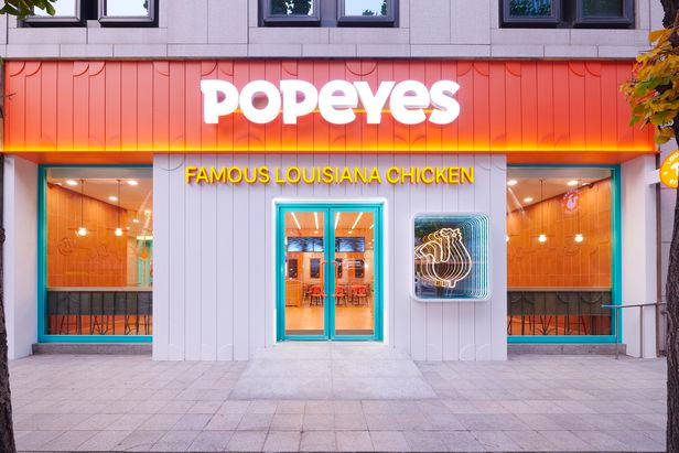 品牌Popeyes位於韓國首爾江南站的分店外觀，顯示店鋪標誌和品牌顏色的招牌和外立面。