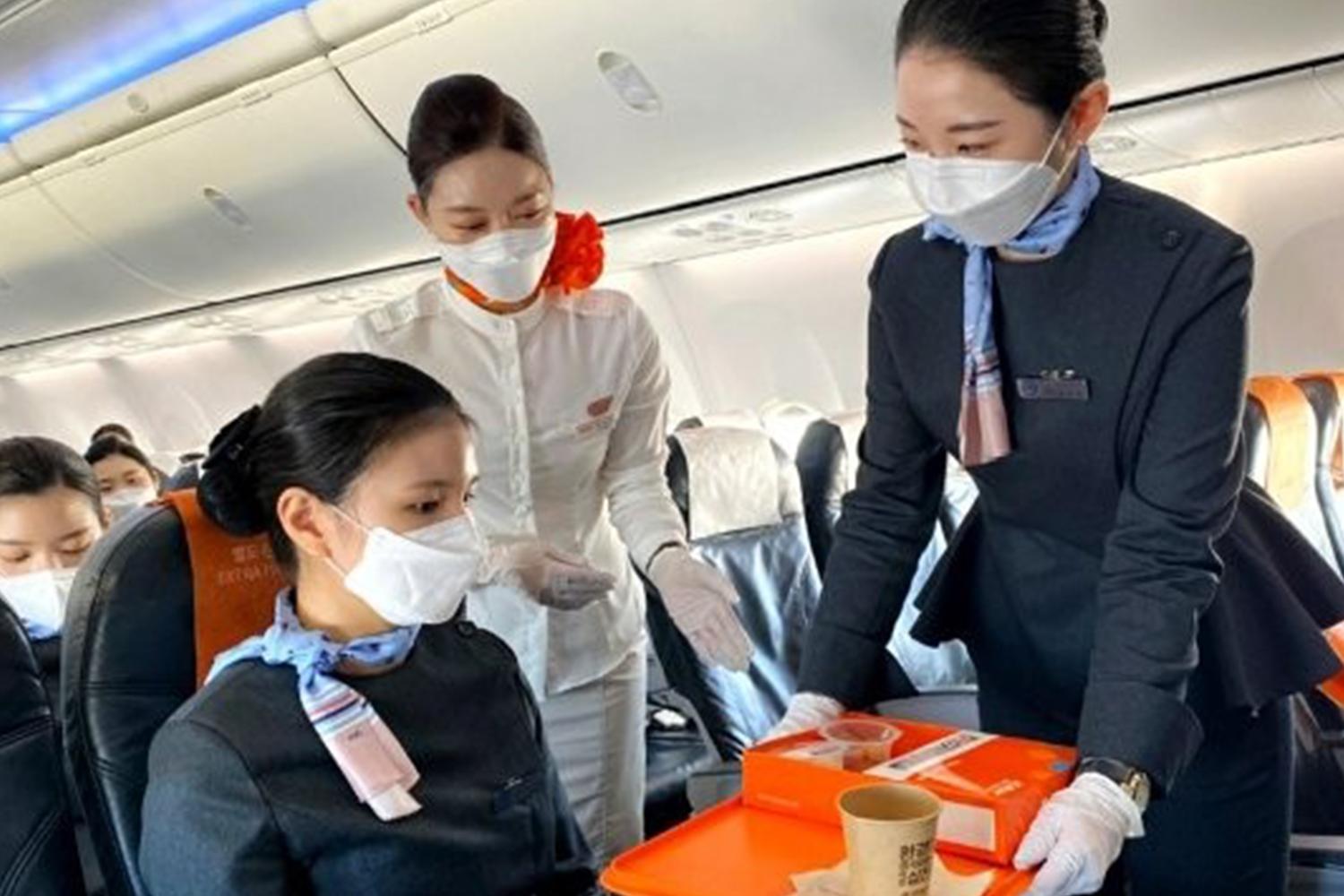 濟州航空機艙內，空姐穿著制服，正在為乘客提供服務與餐飲，展現舒適愉快的飛行假期。