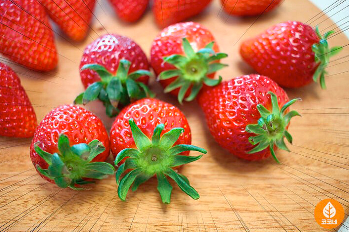 多個韓國新鮮士多啤梨在木板上排列，顯示選擇鮮嫩紅色果實的重要性與新鮮度。