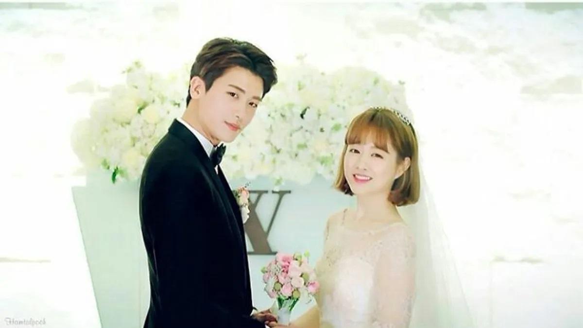 คู่บ่าวสาวในชุดแต่งงานสีขาวพร้อมแบ็คกราวด์ดอกไม้สีขาวในงานแต่งงาน