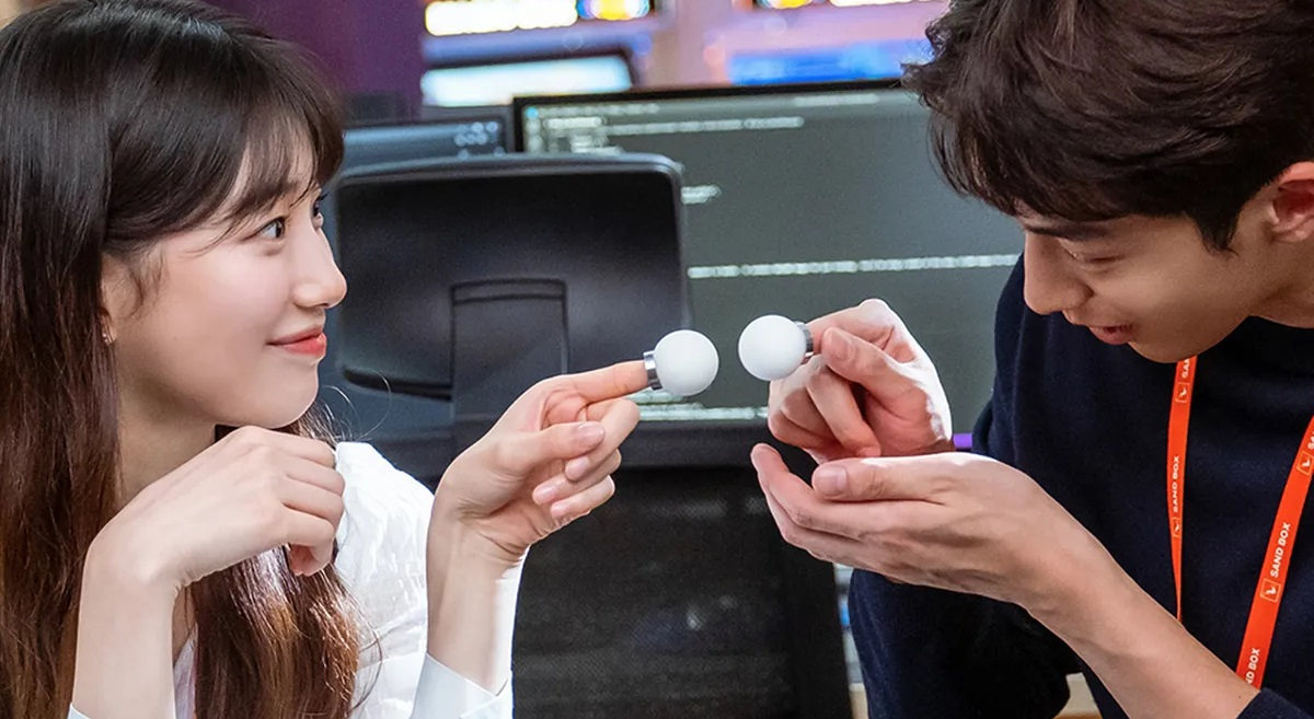 ฉากจากซีรีส์เกาหลีเรื่อง Start Up นักแสดงชายและหญิงกำลังสนทนาอยู่ในสำนักงาน โดยมือทั้งสองถือวัตถุทรงกลมสีขาว