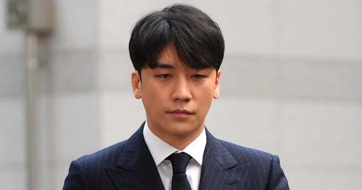 บุคคลสองคนยืนอยู่บนถนน โดยมีคนหนึ่งสวมหมวกบีนนี่สีดำและเสื้อแจ็คเก็ตสเวตเตอร์ลายทางสีแดงเข้ม อีกคนสวมเสื้อแจ็คเก็ตขาว